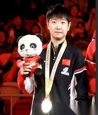 就挺魔幻的。
领导让她低调点，往边上站，别太突出。
结果呢？全场就她那块金牌，闪