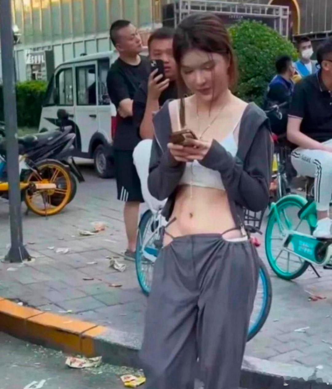 在超市旁边看到一女孩，穿着这样裤子在街边逗留，身后的男子正偷偷窥望！实在让人担心