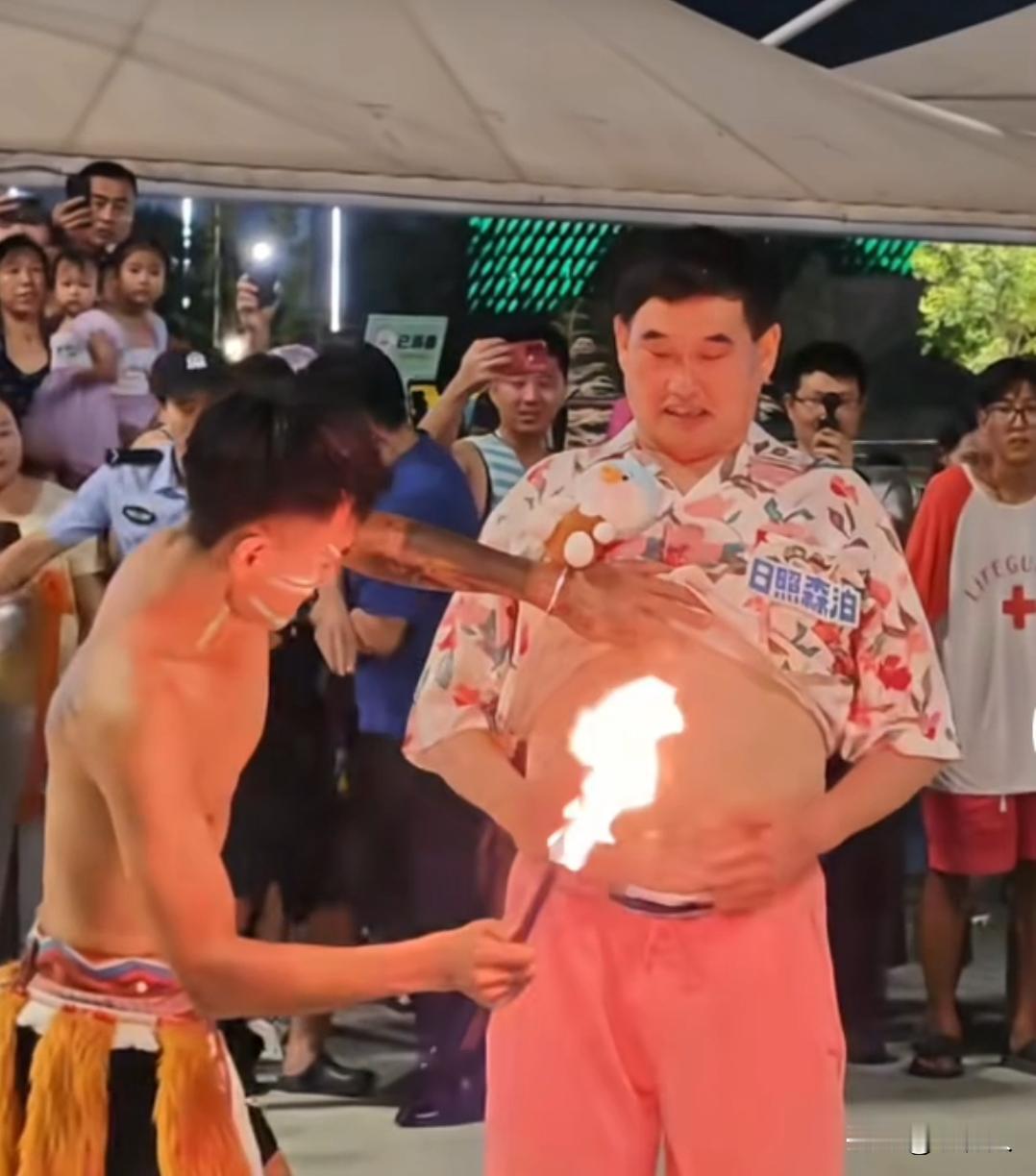 乐园夜间民族特技表演环节，喷火艺人近距离表演火焰特技。火把在朱之文腹部前方展示，