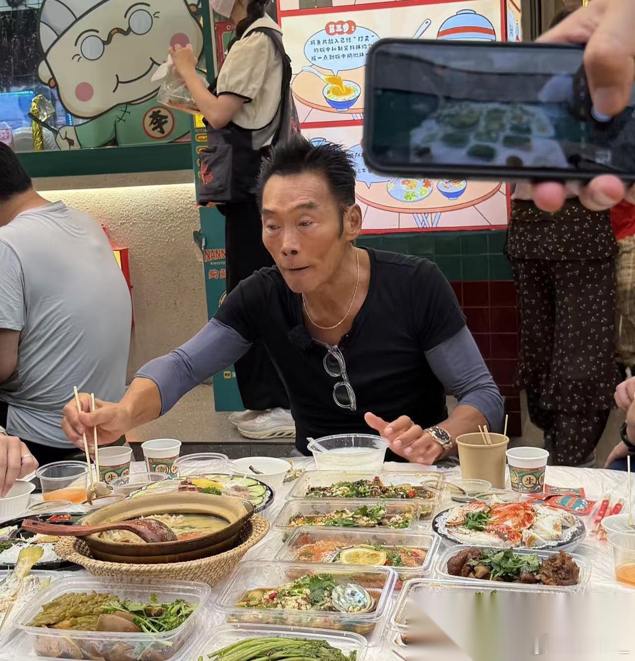 62岁港星郑浩南现身广东汕头一家餐馆吃生腌菜，他坐在街边排队，点了一大桌海鲜，在