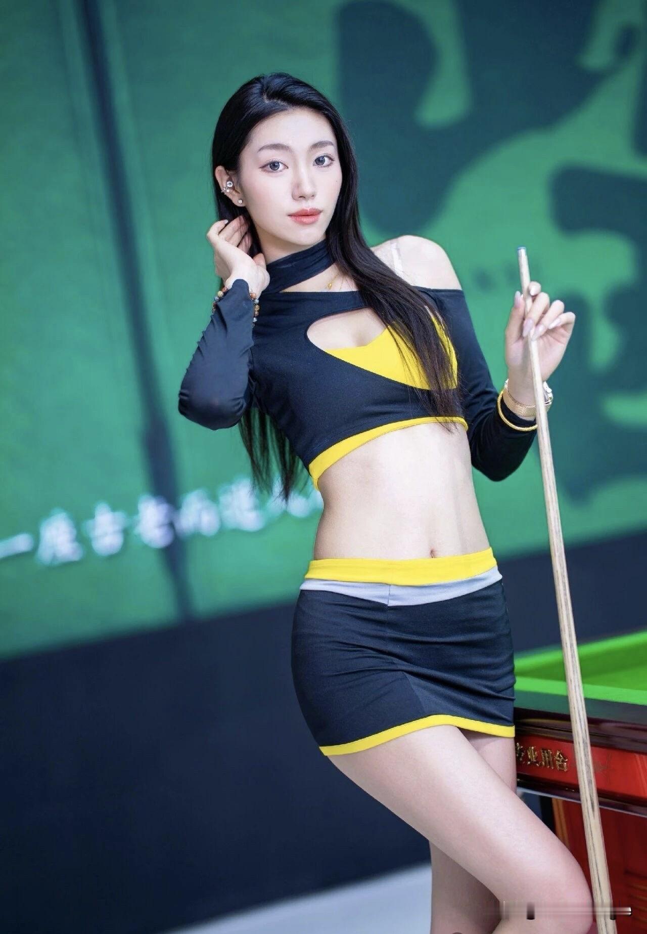 这位美女靠在台球桌边，穿着时尚。