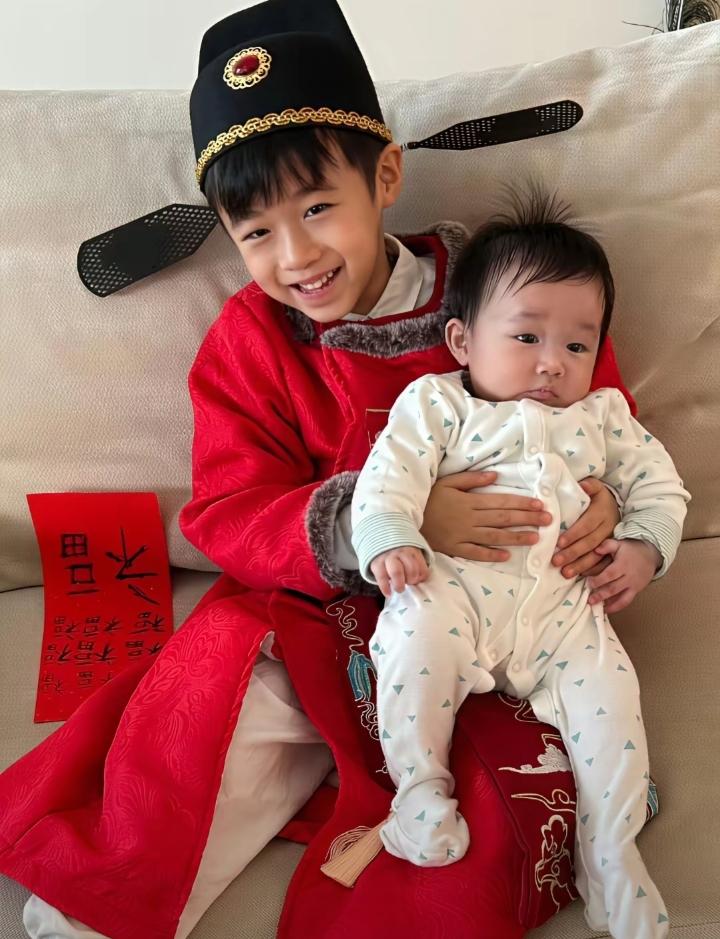古巨基除夕晒二胎儿子的正脸，小儿子被哥哥温柔抱着，肉嘟嘟软萌可爱，眉、眼、鼻子，