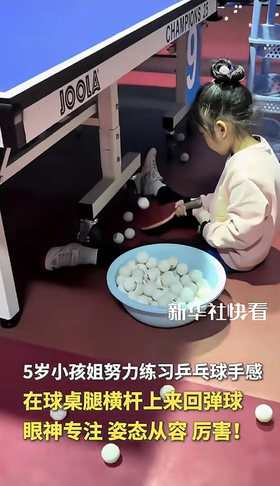 这位5岁的“小孩姐”太厉害了！她没在正规球台上练球，而是蹲在乒乓球桌腿的横杆旁，