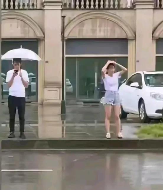 太尴尬！广东惠州正天降大雨，有一名男子撑着雨伞在等车，有一名女子左顾右盼，没有找