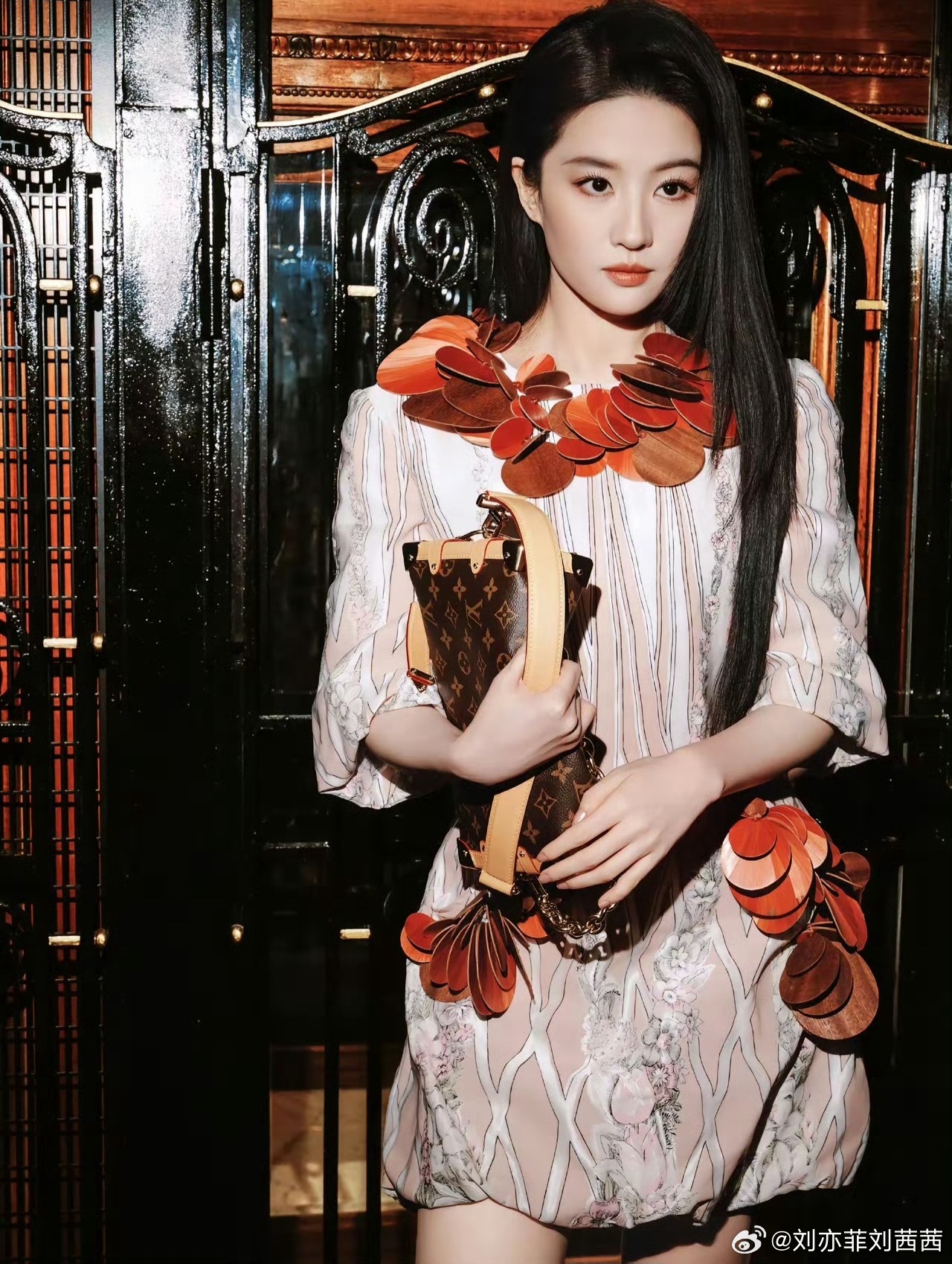 刘亦菲身着浅粉底色裙装，细腻花卉与竖条纹印花相映成趣，七分袖设计温柔又利落。红棕