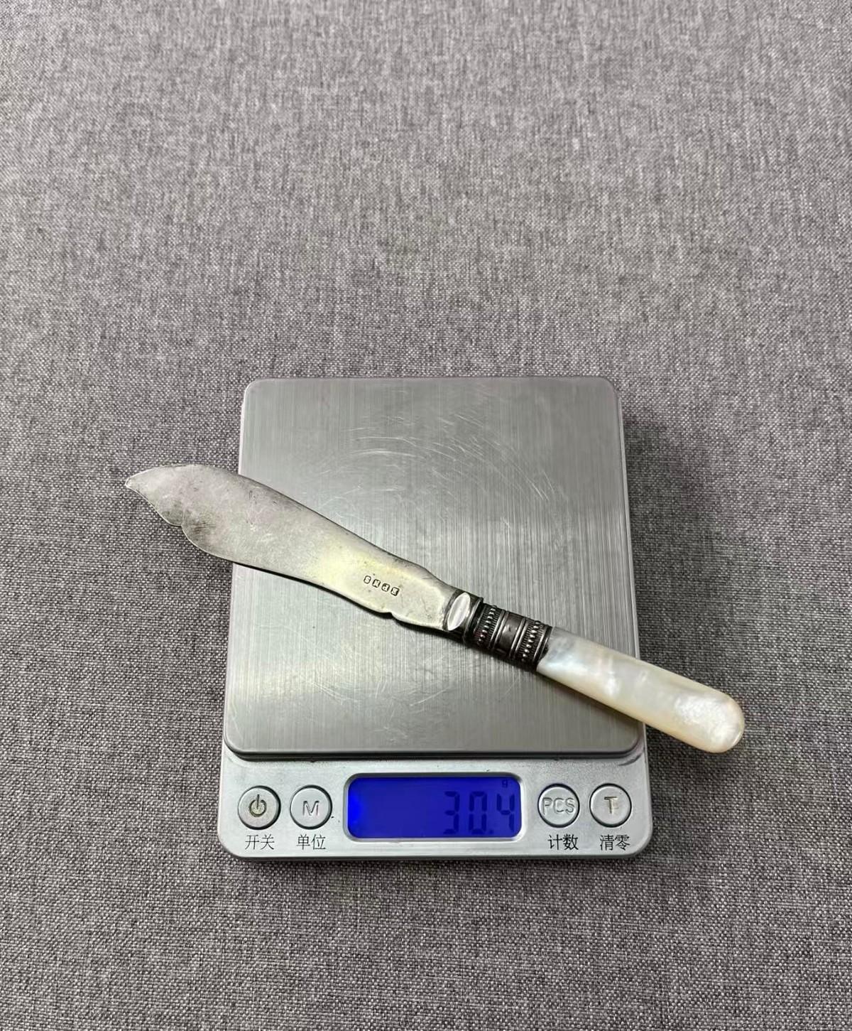 昨晚收了一捆旧书，拆绳子时掉出来一把刀，上面有手工錾刻的花纹，刀柄是白色贝壳的，