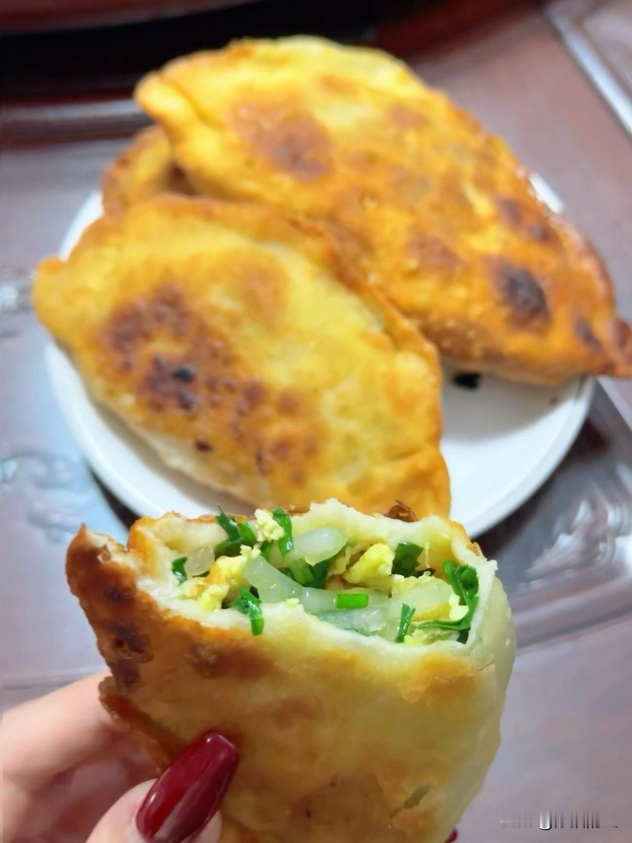 今天吃到的韭菜鸡蛋盒子也太香了。
刚出锅的盒子外皮煎得金黄焦脆，边缘鼓着泡泡，咬