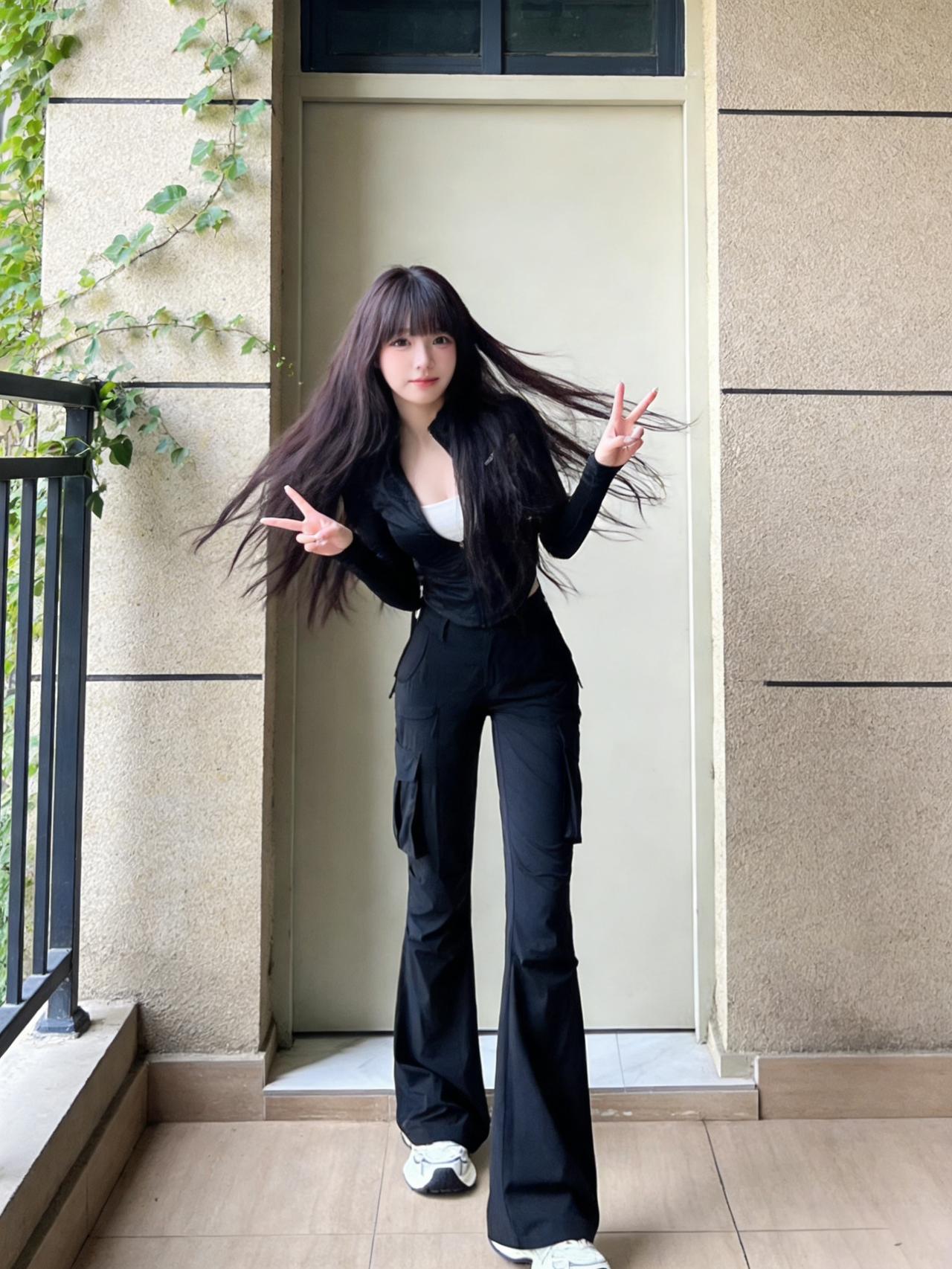 她一身黑色套装，像夜色裁成的铠甲。皮衣泛着冷光，金属拉链斜斜划过胸前，裤脚利落收