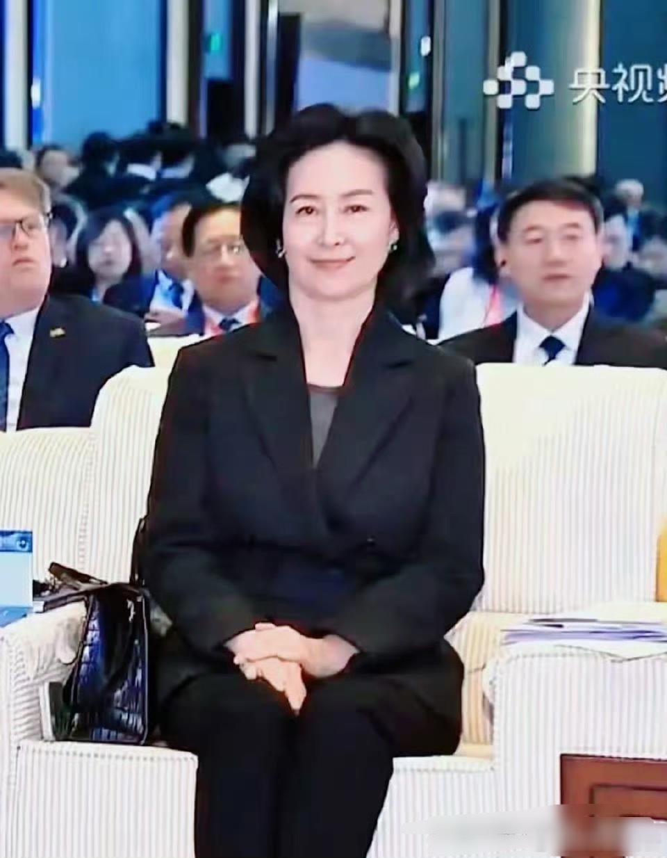 何超琼上电视了，穿黑色西装坐姿端正，手边放40w爱马仕也不扎眼，气场强大 