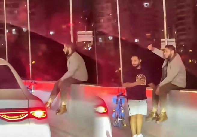 11月11日，上海，2名外国人骑共享单车上高架，一人淡定的坐在高架上，另一人则在