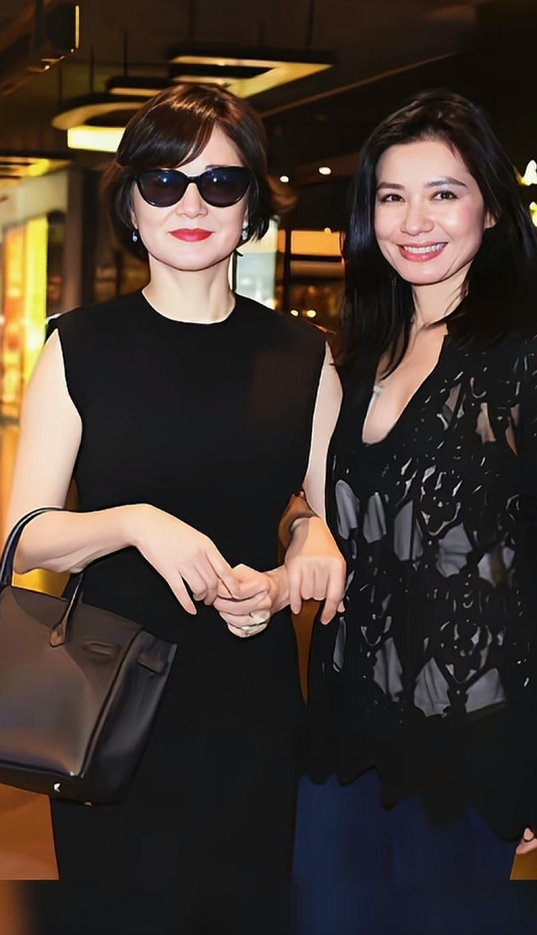 两位美女手牵手逛街，笑容灿烂。早期的一张照片非常有年代感。那时候真年轻，都认识吧