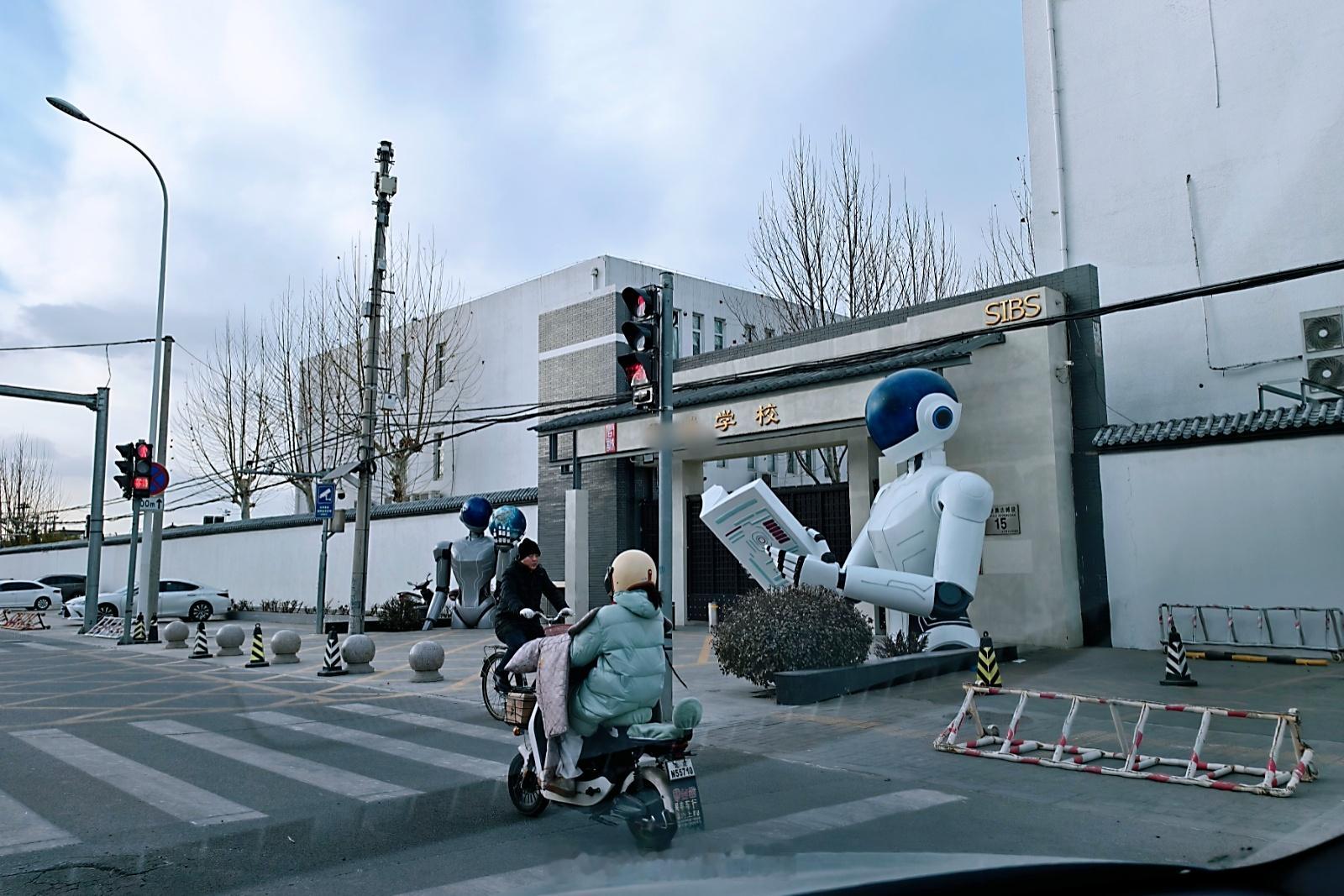 这学校门口不知啥时候摆了俩雕塑，感觉多少有点怪。潜台词莫不是书让机器人去读，人类