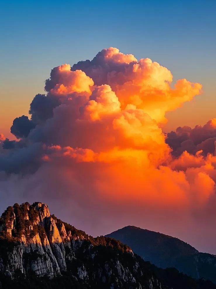 庐山上空，云朵被夕阳染上金红、橘红，形态多变，像蓬松棉花糖，又似奔腾骏马。筑峰顶