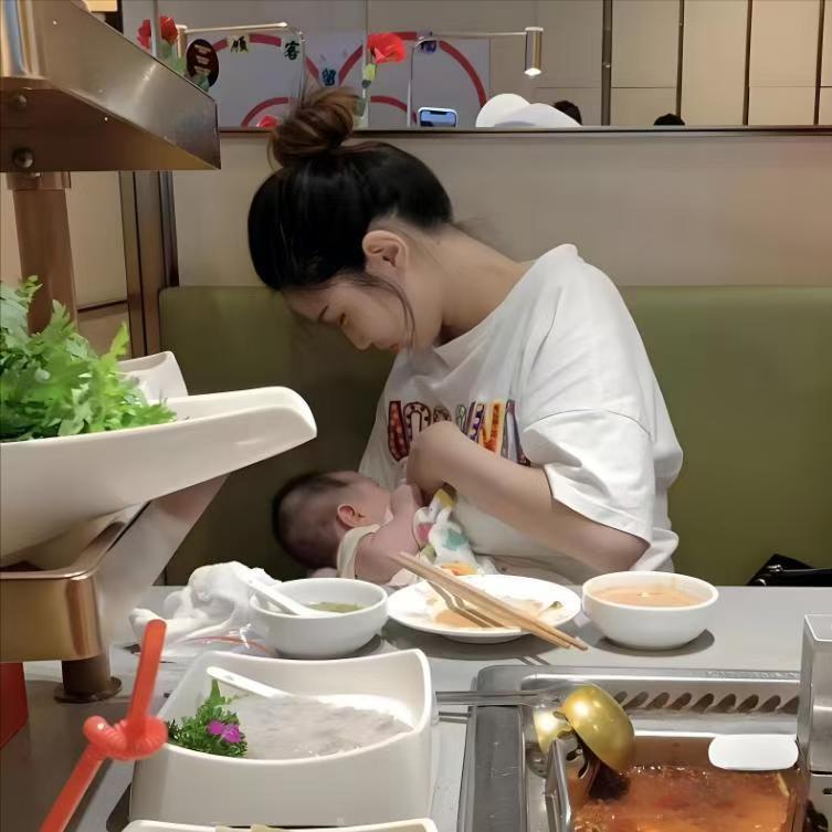 在火锅店的一隅，她专注地给孩子哺乳，周围是热腾腾的火锅和各色餐具，喧闹的环境似乎