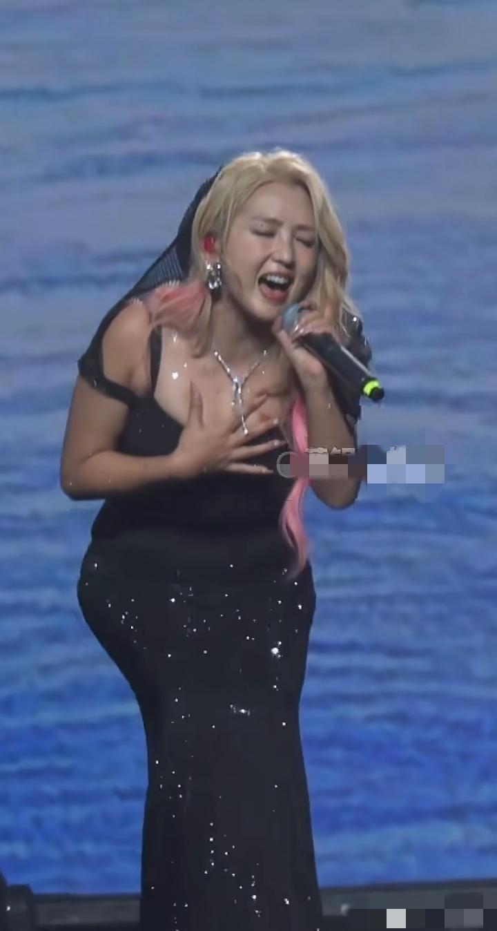 镜头中的何洁身材丰腴，香肩半裸，金粉发垂肩，螓首蛾眉，齿如编贝，双臂抡圆，一手拿