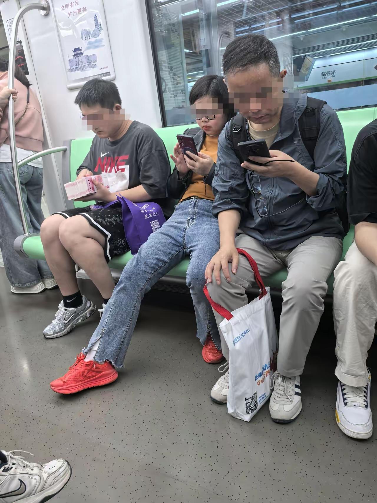 地铁上很多人一般都是玩手机，或坐在椅子上睡觉，很少见到对面这个小伙子拿了一叠钱在