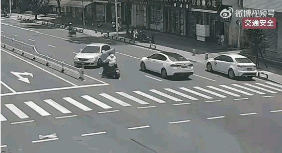 马路上，一个男子骑着摩托车，撞到了一辆正在掉头的轿车车头，摩托车被撞的支离破碎，