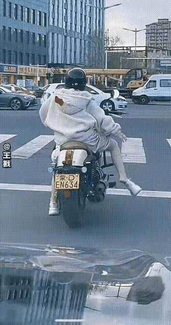 这个美女在等绿灯时脱鞋挠痒痒，绿灯亮时竟然自顾自的把摩托车骑走，一只崭新的鞋子落