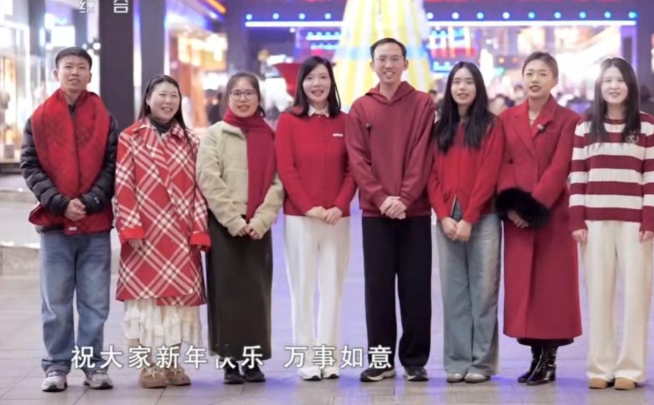 红装的人们并肩而立，一句“新年快乐，万事如意”的祝福，满含普通人对新年的质朴期许