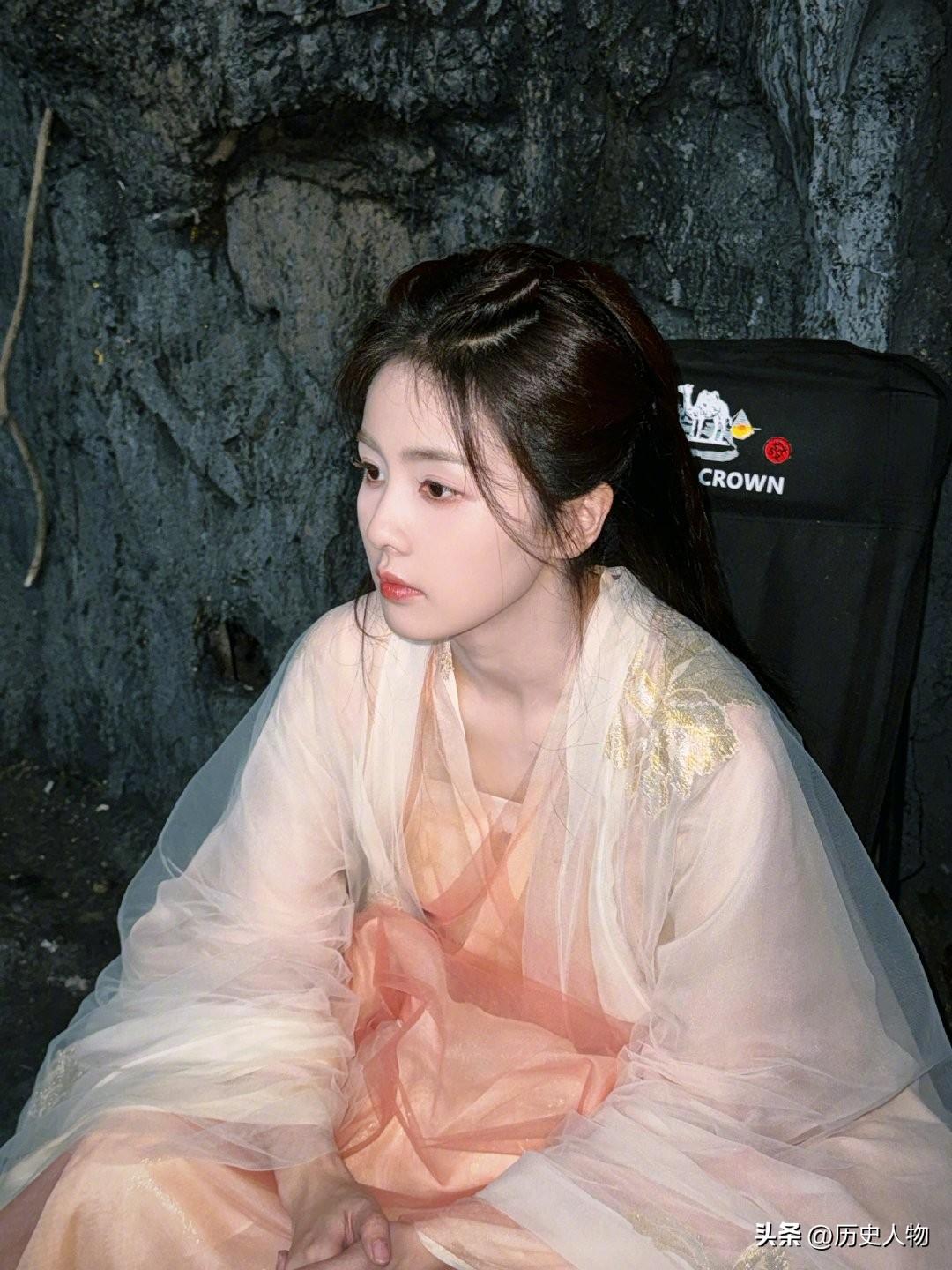 沉静的古典美人，一袭轻纱，静坐于石壁前。