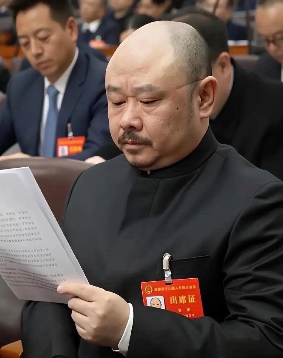 成都两会现场，人大代表罗林同志身着深灰色中山装，佩戴着红色出席证。
此时，他已不