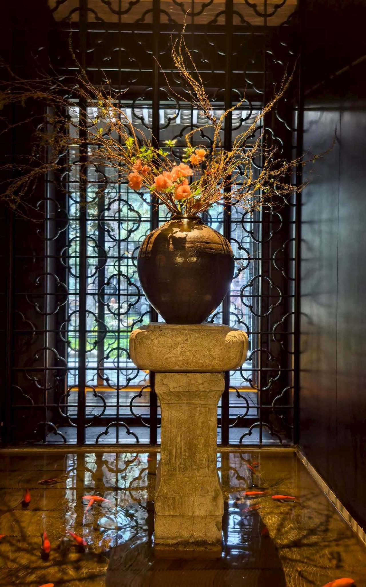 黑瓦白墙映着松影，锦鲤在水间游弋，古窗棂漏进细碎天光，陶罐里的花枝轻摇，油纸伞斜