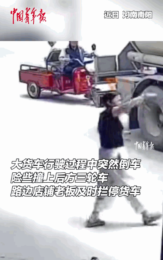 功德无量！河南的一条街边，一辆庞大的货车正在轰轰隆隆地往后倒车，司机坐在高高的驾