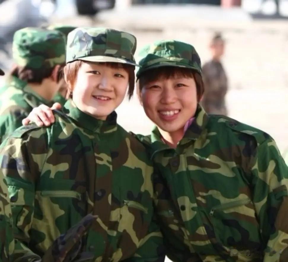 两位国乒女队队员，穿着迷彩服军训的合影，两人都笑的阳光灿烂。左边是陈梦，那时她很