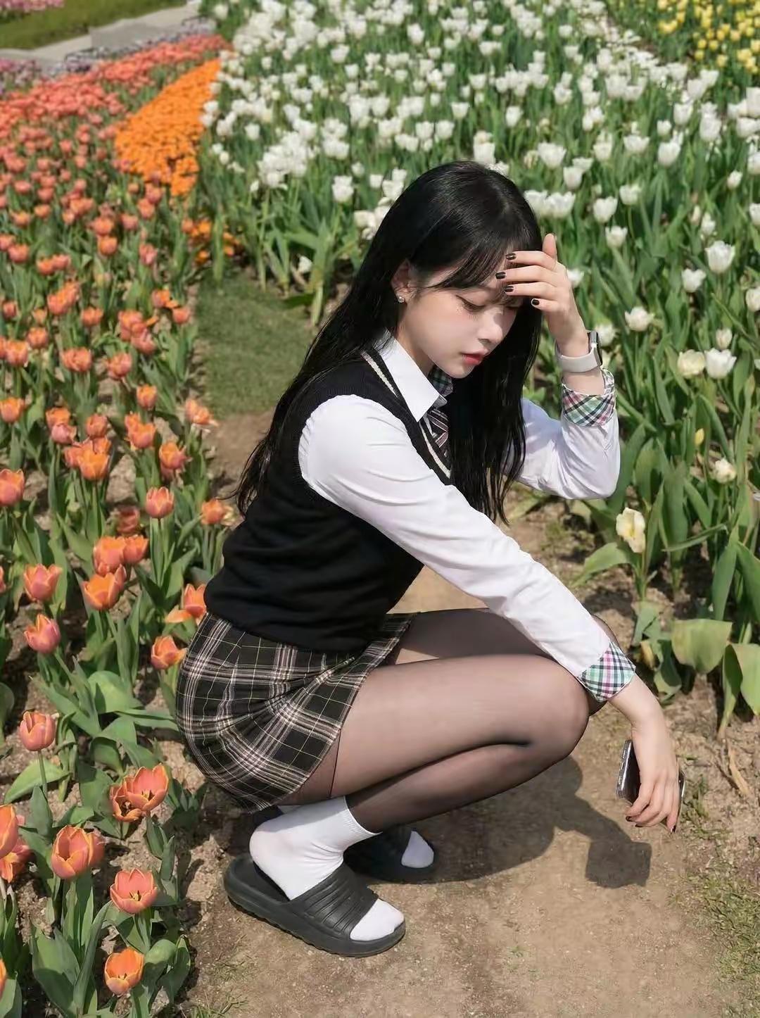 少女在花田中蹲下，黑发白衣，静谧如画。