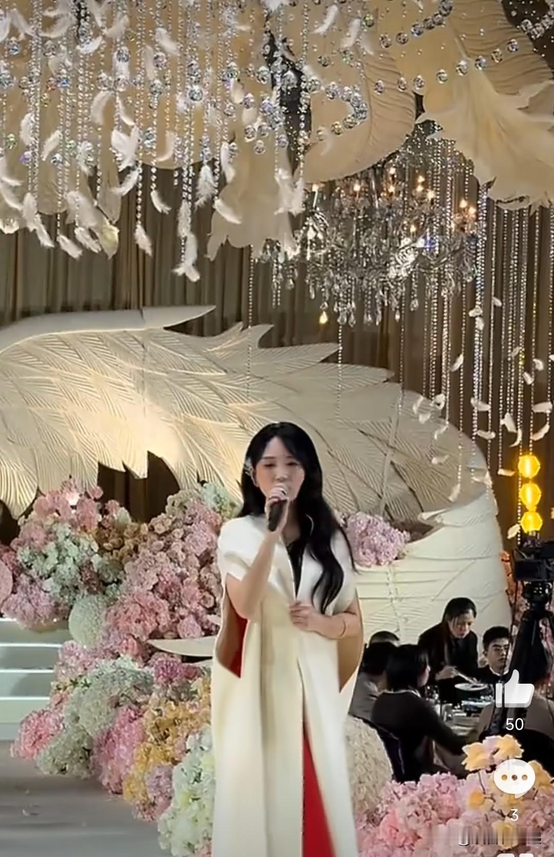 曾经红遍大江南北的歌手金莎，现身婚宴演出。舞台上的她身着亮眼红裙搭配素雅白披肩，