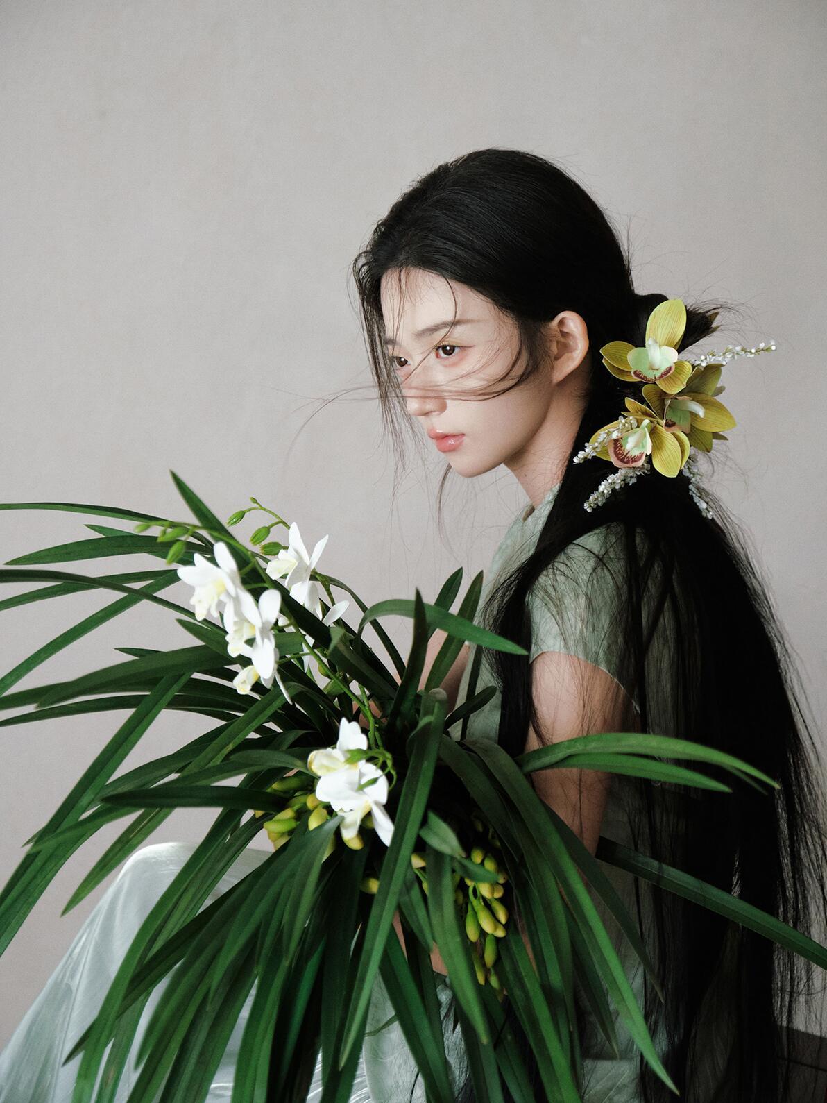 作品将人物与兰花的融合推向极致，模特半隐于兰草之后，仅露出的面部与花枝形成虚实交