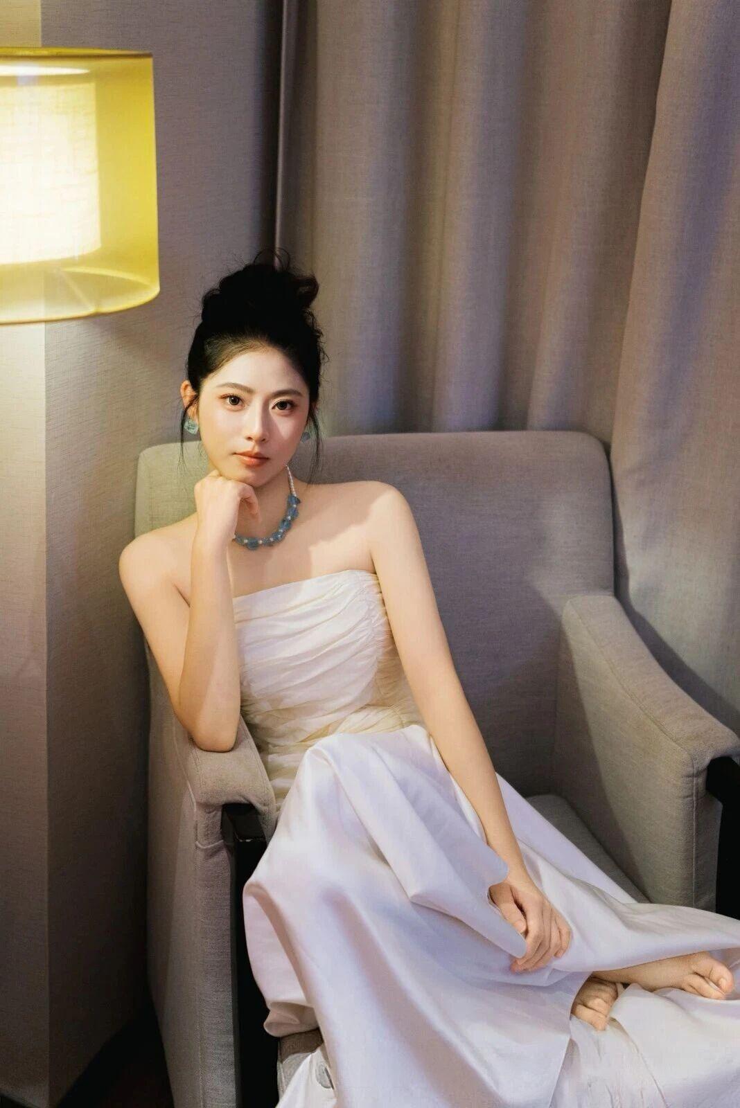 什么样的穿搭可以成为气质女神?这组照片展现了一位身着白色抹胸长裙的年轻女性，在室