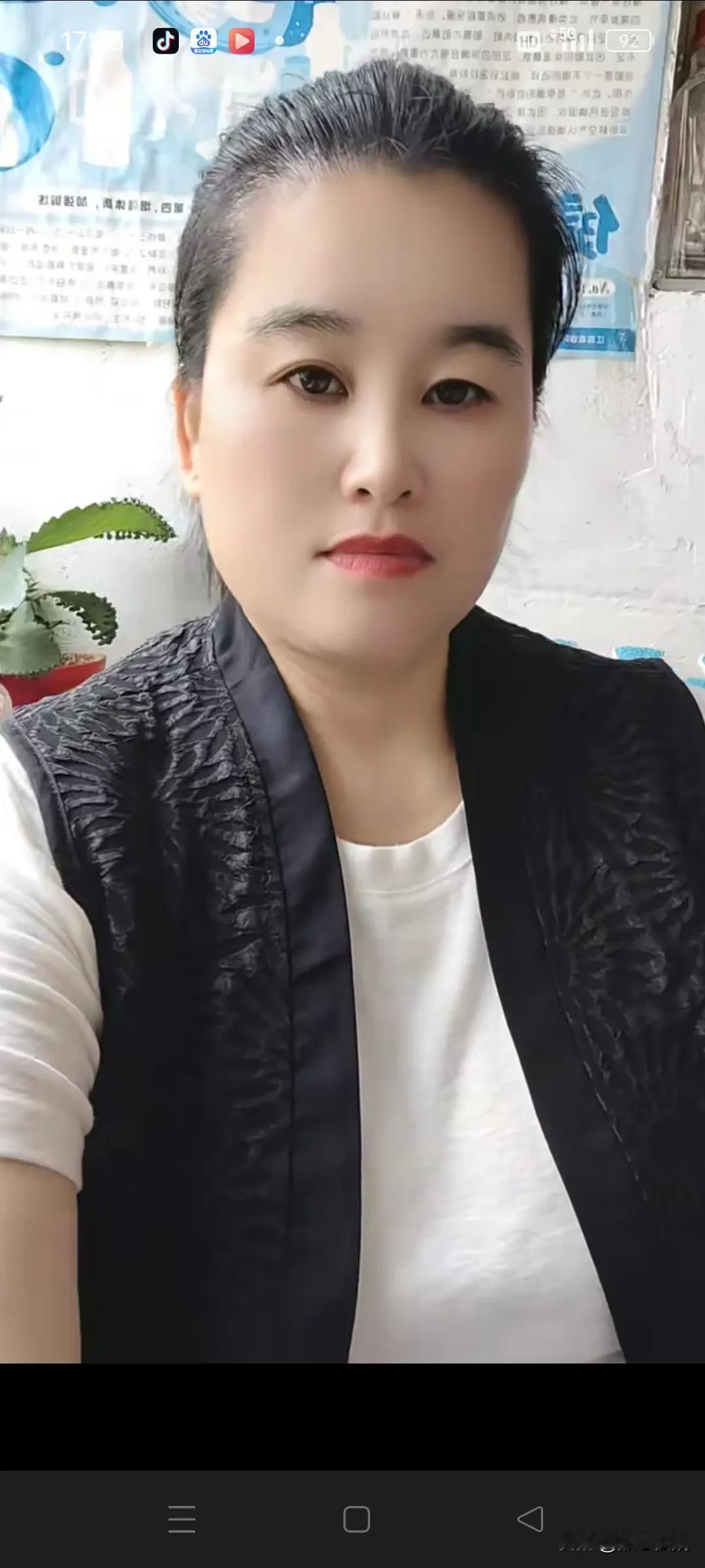 这位女士穿着黑色背心，白色T恤。