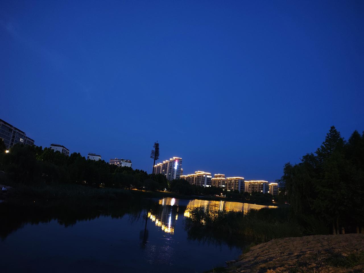 随手一拍的黄昏太阳下山，夜幕降生，华灯初上，光影倒映在湖面黄昏日落景 手机抓拍落