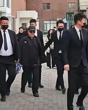 这是谁啊，好眼熟，一袭黑衣黑帽，带着墨镜，身边一群保镖。
保镖是清一色黑口罩黑衣