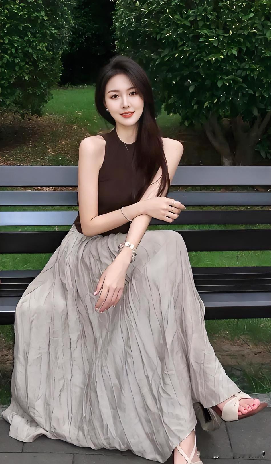 绿荫斑驳，定格她娴静的坐姿。咖色上衣交织温柔，浅灰裙摆摇曳诗意。那一抹明媚的笑靥