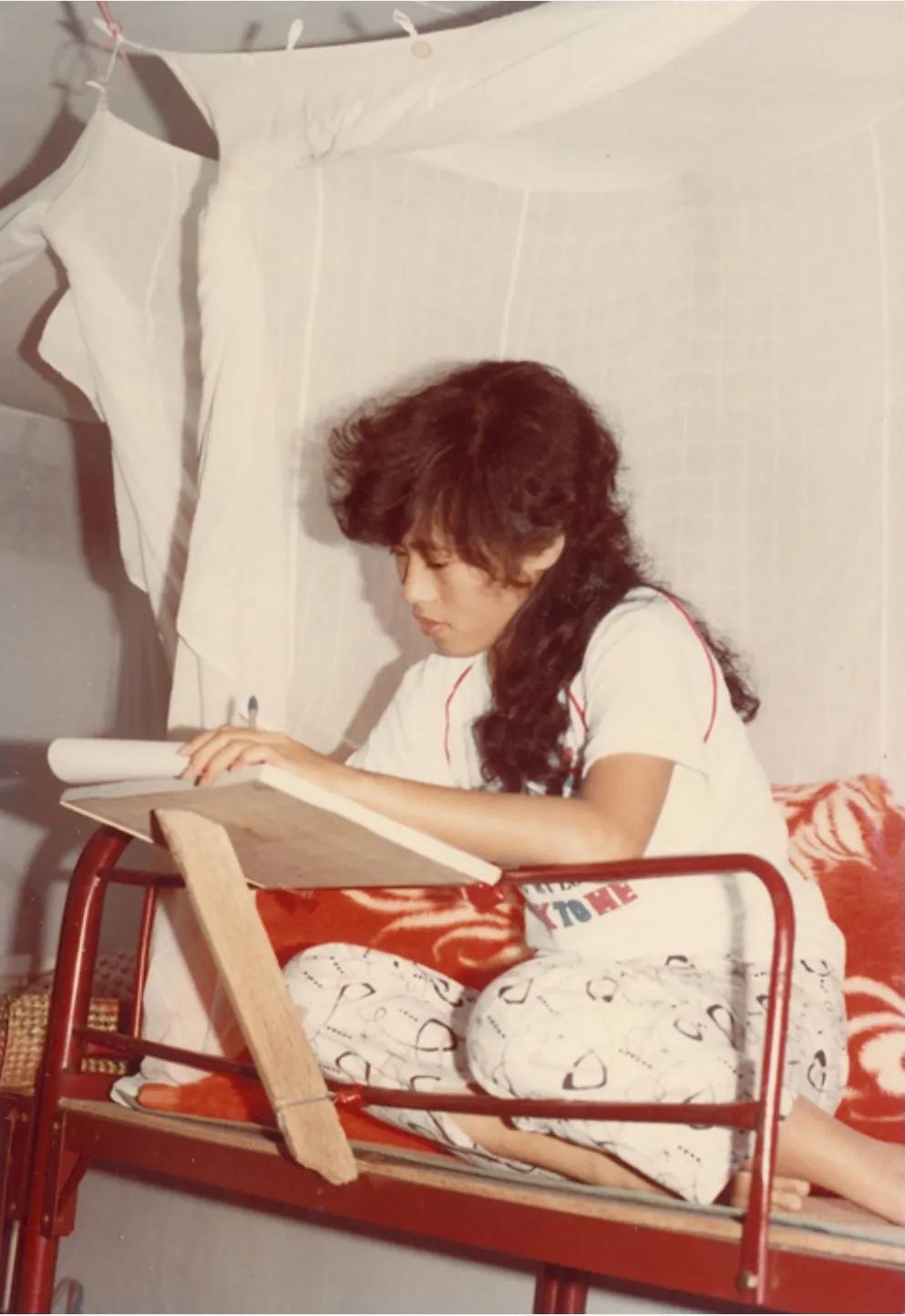 1982年，深圳，一名“打工妹”坐在宿舍的床上给家人写信，照片中的她留着时髦的发