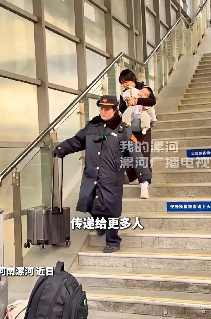 火车站内，一位妈妈抱着熟睡的宝宝下步梯，手中还提着一个行李箱，非常不方便。这时站