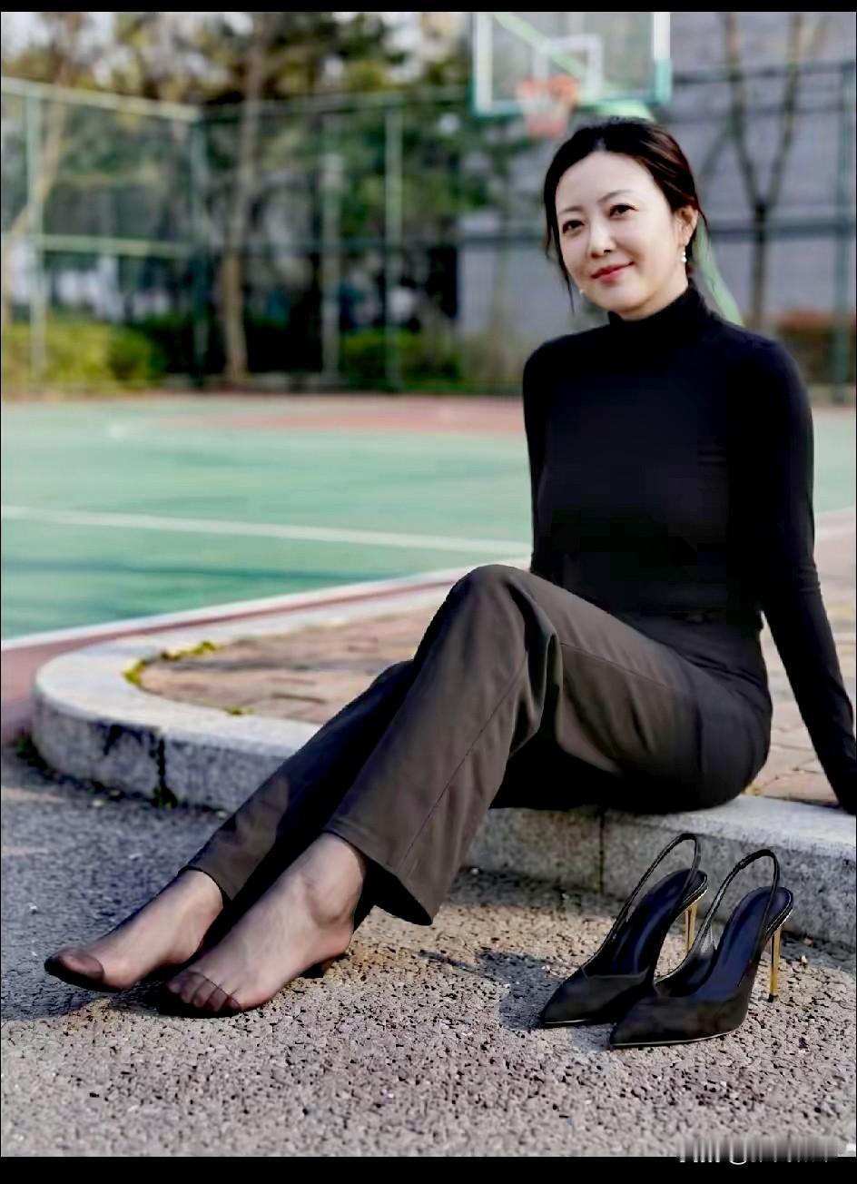 褪去青涩的温婉从容，自带岁月沉淀下来的舒展气韵。一身简素黑衣，静坐在球场边，笑意