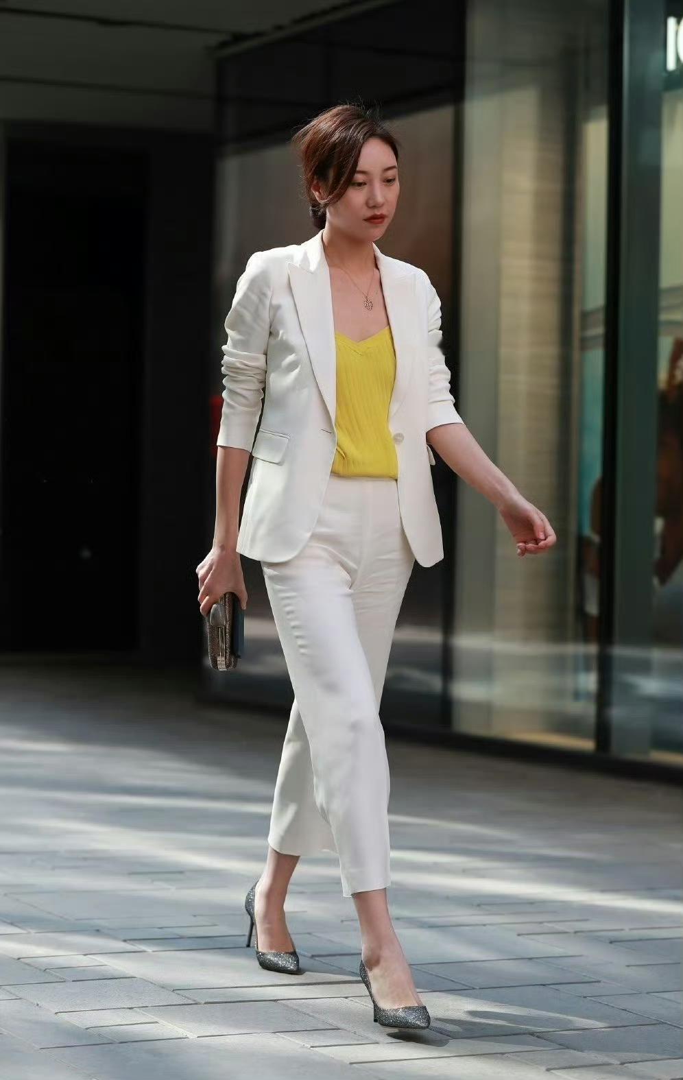白色西装套装版型利落，西装的挺括剪裁与九分裤的设计营造出干练的职场形象，整套穿搭
