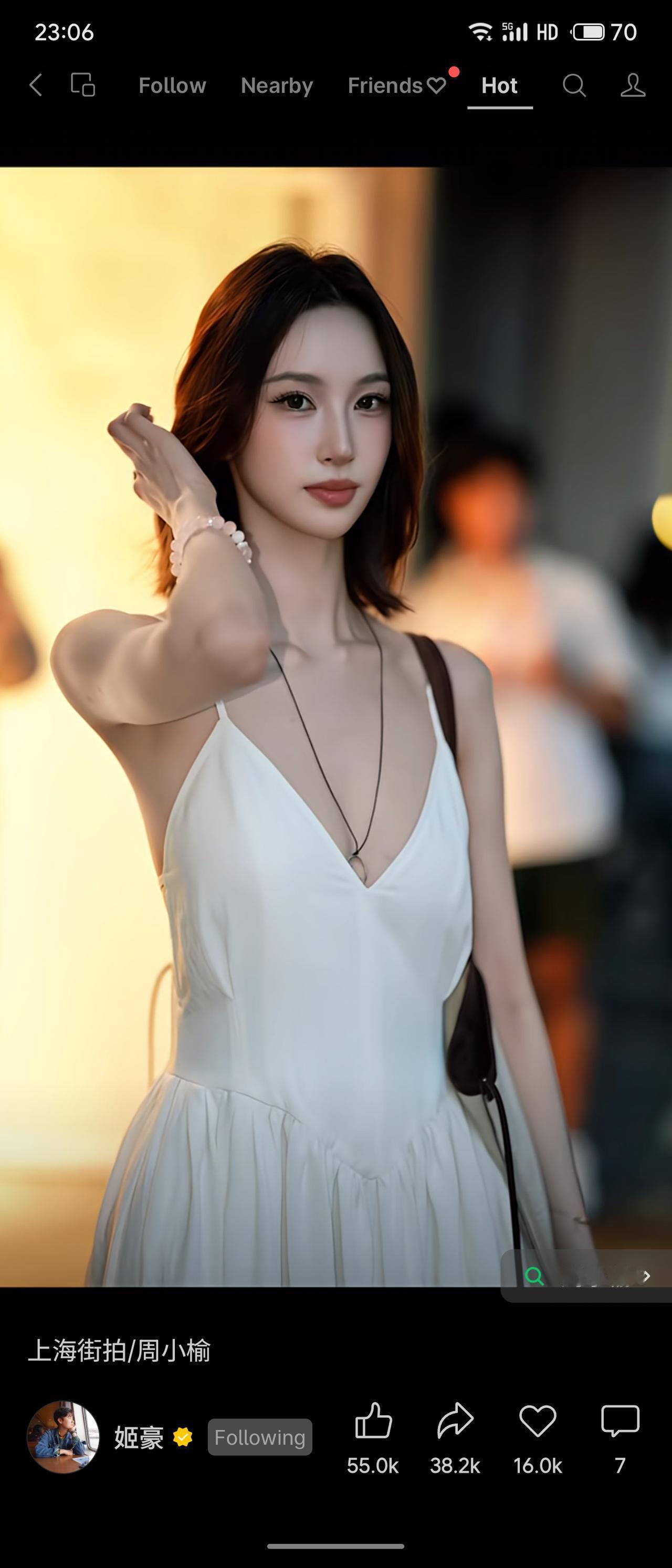 暮色降临的上海街头，暖黄路灯温柔洒落。周小榆一袭米白深V吊带长裙，优雅舒展，肩挎