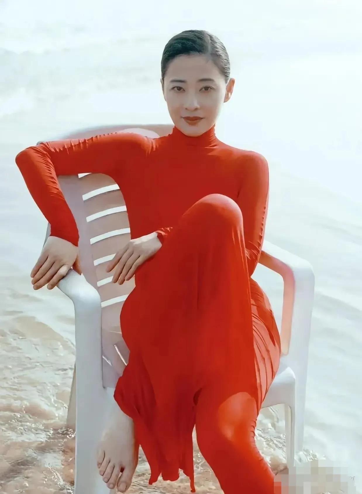 这张图片是梅婷多年拍摄的照片，地点在海边。
图片中的梅婷一身红色长裙，坐在椅子上