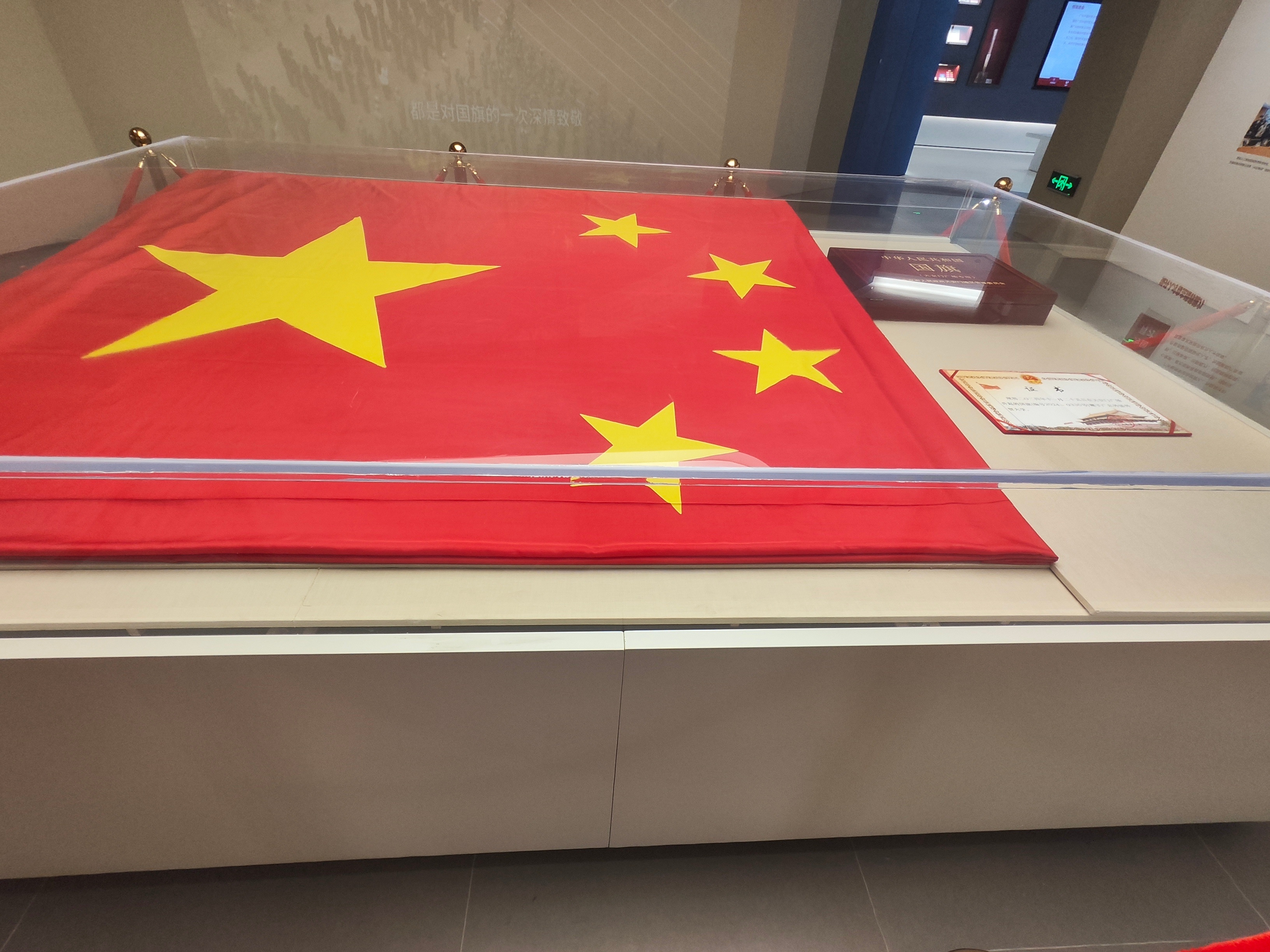 隔着玻璃凝视这面五星红旗，它安静地躺在展柜中，却仿佛有千钧力量。那抹红是热血凝成