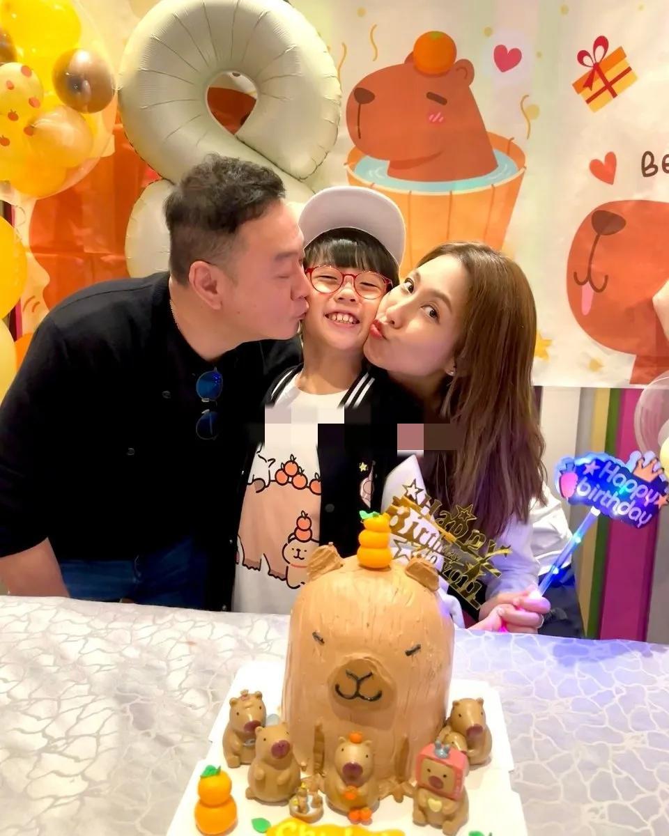 香港女明星陈敏之的儿子今年8岁，小小年纪已经带上眼镜了，爸爸妈妈一边一个亲吻，小