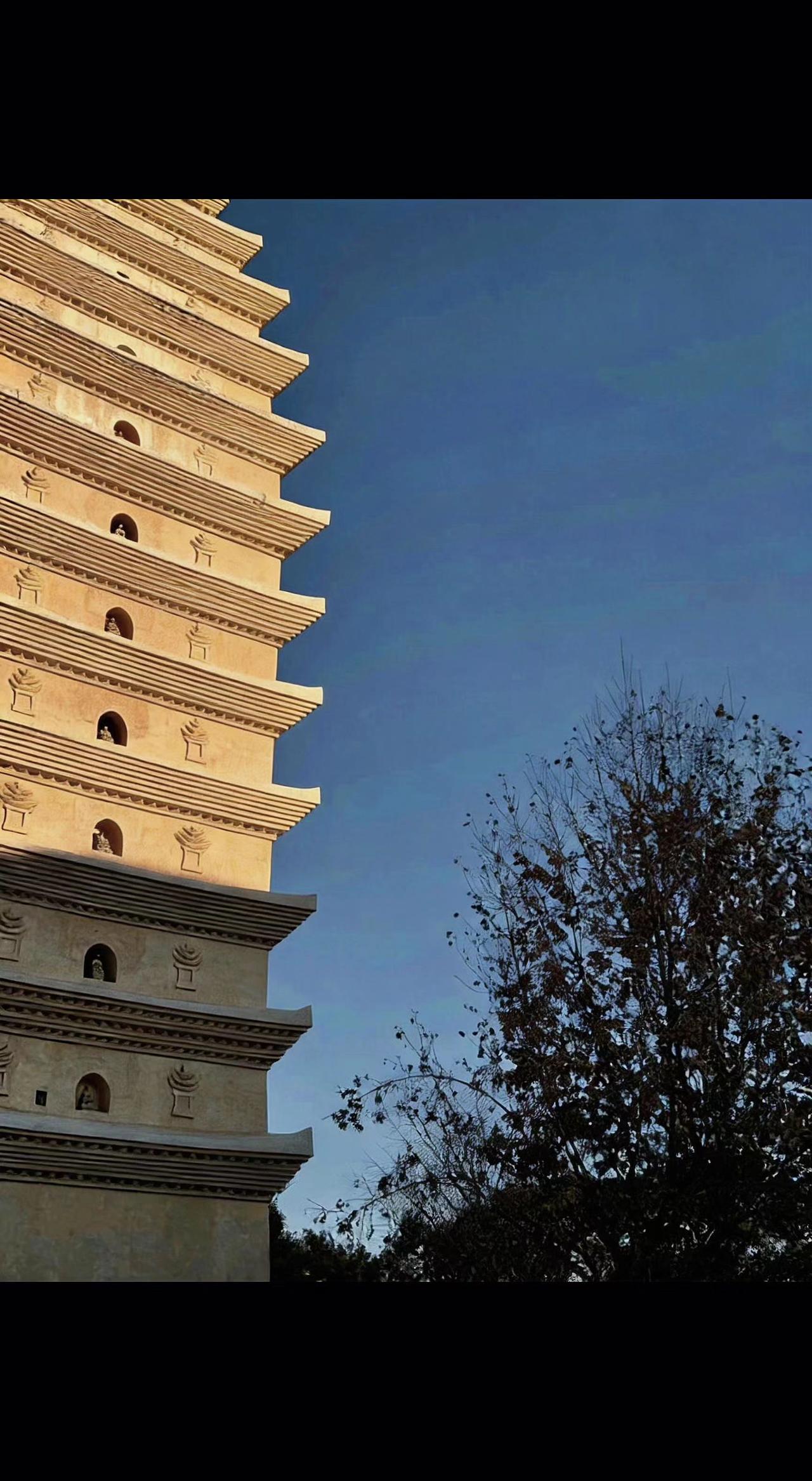 🏯斜阳给古塔镀了层金箔，檐角风铃在风中沉默。树影婆娑，千年光阴不过一砖一瓦的斑