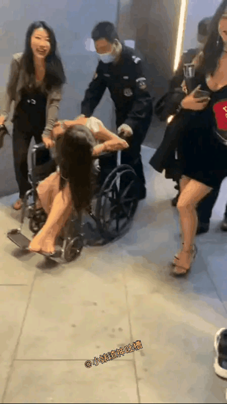 女子坐在了轮椅上，看样子像是喝多了，不像是生病了，如果真是生病的话，这些同伴也不