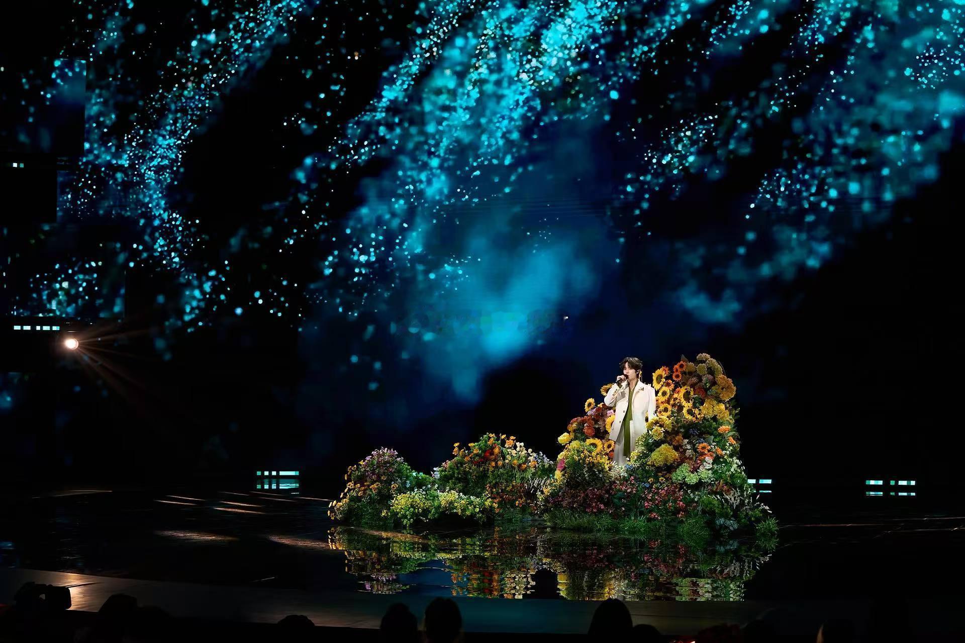 井胧被一大片花团围住唱歌2026川渝春晚 满台的鲜花都成了陪衬，井胧站在那里就像