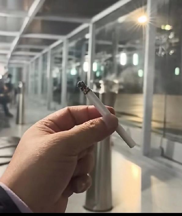 张雪给陌生大哥举着一根点燃的香烟，没有想到的是大哥进了厕所，原来是取水浇灭垃圾桶