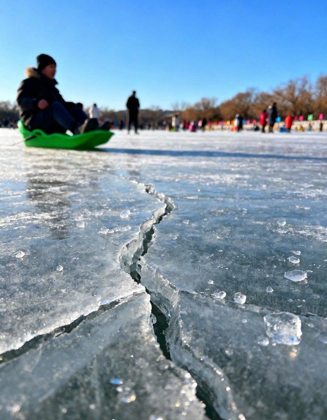 网友：应该是气温太高阳光又好，什刹海冰场开始出现裂缝了，一直有工作人员在拿大袋的