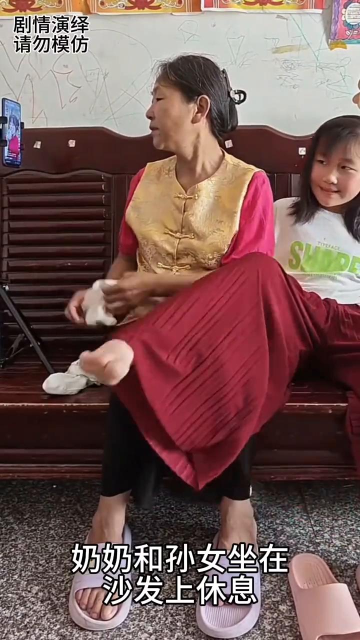 奶奶看手机入迷时将袜子穿孙女脚上了，这一幕真的太搞笑了。
奶奶和孙女坐在沙发上休